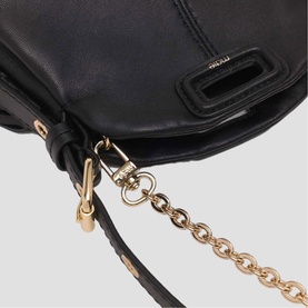 Maje black leather bag close-up detail showing gold chain strap and knot hardware accent.
