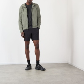 Model wearing Arcteryx Atom SL Hoodie Jacket in Forage green with black shorts and black chunky trainers.