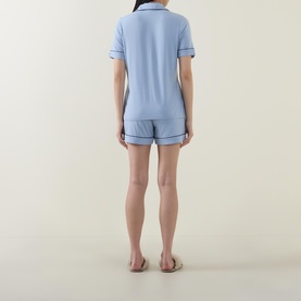Model wearing Gingerlilly Sadie Contrast Piping Pyjama Set in blue, rear view, showing short-sleeve top and shorts with contrast piping detail.