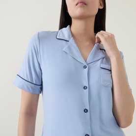 Model wearing Gingerlilly Sadie Contrast Piping Pyjama Set in blue, short-sleeve notch lapel top with navy contrast piping and chest pocket visible.