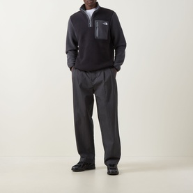 Model wearing North Face Yumiori Half-Zip Sweatshirt in Black/Grey fleece with zipped chest pocket, styled with grey trousers and black shoes.