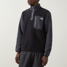 Model wearing North Face Yumiori Half-Zip Sweatshirt in Black/Grey fleece with zipped chest pocket and embroidered logo, styled with grey trousers.