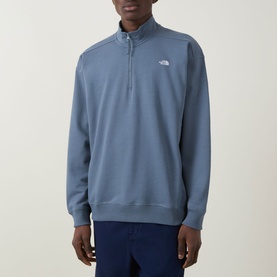 Model wearing North Face Essential Light Half-Zip Sweatshirt in Granite Grey, featuring half-zip neckline and embroidered logo, styled with blue