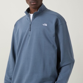 Model wearing North Face Essential Light Half-Zip Sweatshirt in Granite Grey, showing half-zip neckline and embroidered chest logo.