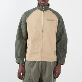 Model wearing Pleasures beige casual jacket with olive green quilted contrast sleeves and funnel neck, zip fastening