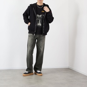 Model wearing Pleasures black zip-up cotton hoodie with graphic tee, khaki wide-leg jeans and platform trainers.