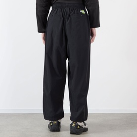 Model wearing Pleasures black nylon casual trousers, shown from behind with elasticated waist and wide-leg fit, styled with dark chunky shoes.