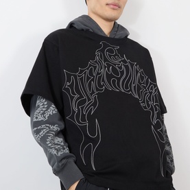 Model wearing Pleasures black cotton hoodie with grey graphic flame print, styled over grey long-sleeve top with dragon print