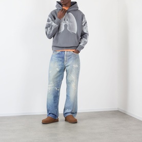 Model wearing Pleasures grey cotton hoodie with lung graphic print, styled with light wash distressed jeans and tan suede loafers