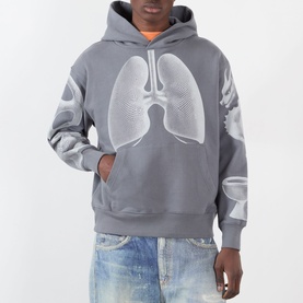 Model wearing Pleasures grey hoodie with oversized white lung graphic print, paired with light-wash jeans