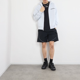 Model wearing Pleasures grey cotton zip-up hoodie with black T-shirt, black shorts, and black trainers.