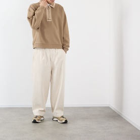 Model wearing Pleasures tan cotton sweatshirt with collar detail, styled with cream wide-leg trousers and multicolour trainers.