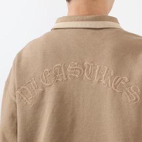 Model wearing Pleasures tan cotton sweatshirt, back view showing embroidered arc logo lettering across shoulders