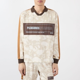 Model wearing Pleasures ecru cotton long-sleeve polo top with brown trim, graphic logo print, and tan camo panel detailing