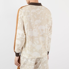 Model wearing Pleasures ecru floral-print cotton sweatshirt, rear view, with brown ribbed cuffs and collar and tan side stripe panels.