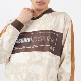 Model wearing Pleasures ecru cotton long-sleeve top with brown graphic logo panel and floral all-over print, amber side stripe detail