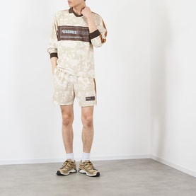 Model wearing Pleasures ecru camo-print long sleeve top with matching shorts and beige chunky trainers with white socks