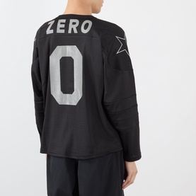 Model wearing Pleasures Jamie Hockey Jersey in black, rear view showing ZERO 0 print, mesh fabric, long sleeves, with black shorts