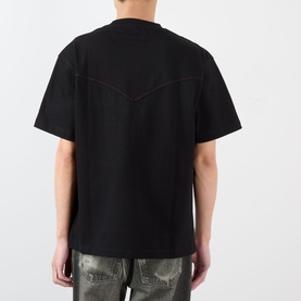 Model wearing Pleasures Ritual Graphic Print Logo T-Shirt in black, rear view, with dropped shoulders and straight hem. Styled with camo trousers.