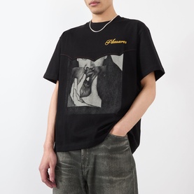 Model wearing Pleasures Ritual Graphic Print Logo T-Shirt in black with front graphic print, styled with a silver chain necklace and grey jeans.