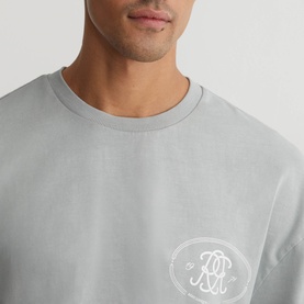 Model wearing Reiss powder blue crew neck T-shirt with tonal circular logo graphic print to chest
