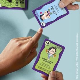 K-Pop Demon Hunters Monopoly Deal card game, hands holding illustrated character cards with purple and green borders