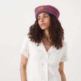 Model wearing Damson Madder Navy & Red Stripe crochet paper sun hat, styled with a white broderie anglaise short-sleeve shirt.