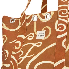 Damson Madder brown cotton tote bag with cream swirl print, silver eyelet detail on handles, close-up view