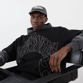 Model with Pleasures Bubble Rip Logo Baseball Cap in grey, styled with black graphic sweatshirt and grey hoodie layer.