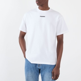 Model wearing Pleasures white cotton T-shirt with small chest logo print, styled with blue jeans.