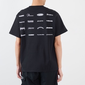 Model wearing Pleasures black cotton T-shirt, back view showing allover white logo repeat print across shoulders and back.