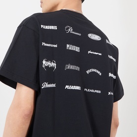 Model wearing Pleasures black cotton T-shirt, back view showing repeated multi-style Pleasures logo prints across the back.