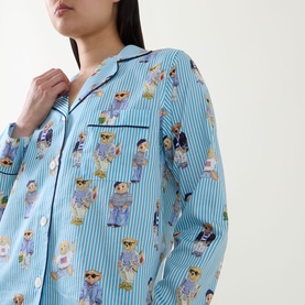 Model wearing Polo nightwear shirt in All Over Bear print, blue stripe cotton with teddy bear motif, notch collar and chest pocket