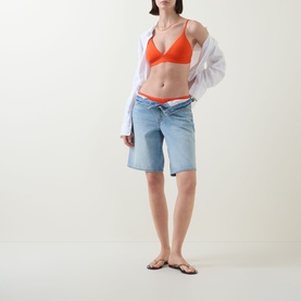 Model wearing Lauren Sunburst Orange bikini brief, styled with light wash denim shorts, white open shirt and tan flip flops.