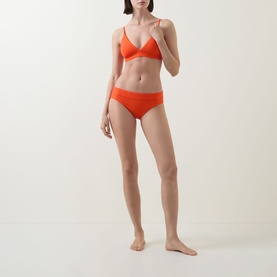 Model wearing Lauren Triangle Bikini Top in Sunburst Orange with V-neckline, narrow straps and gold-tone hardware, styled with matching bikini briefs.
