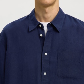 Model wearing Selected Casual Shirt in Ocean Cavern, close-up of navy linen-look fabric with white buttons and chest pocket, styled with white