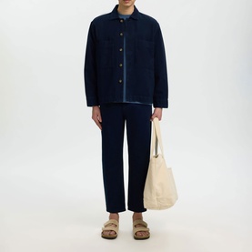 Model wearing Selected dark blue denim casual shirt with matching trousers, styled with a cream tote bag and tan sandals