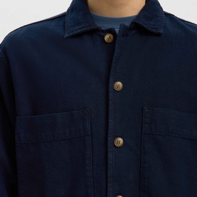 Model wearing Selected dark blue denim casual shirt with chest pockets and gold-tone buttons, close-up view.