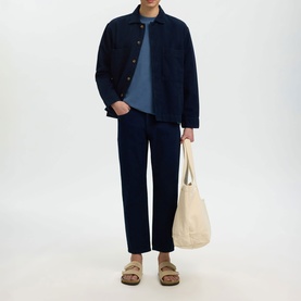 Model wearing Selected dark blue denim casual shirt with matching trousers, styled with a blue tee, tan sandals, and a cream canvas tote bag.