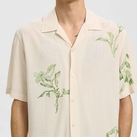 Model wearing Selected Casual Shirt in Egret, short-sleeve camp collar style with green floral botanical print