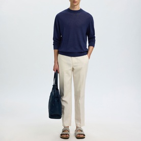 Model wearing Selected Ocean Cavern crew neck knit with cream trousers and sandals, carrying a navy tote bag.