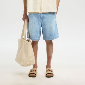 Model wearing Selected light blue denim shorts, styled with a cream shirt, tan sandals, and carrying a natural canvas tote bag.