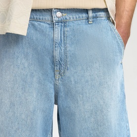 Model wearing Selected light blue denim shorts, styled with a cream top, shown from waist down with wide-leg fit detail.