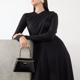 Model carrying Givenchy Antigona Vanity Crossbody Bag in black smooth leather, gold-tone hardware, top handle. Styled with black long-sleeve dress.
