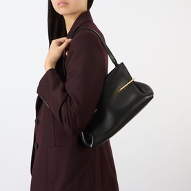 Model carrying Givenchy Pinch Soft Leather Clutch in black lambskin with gold-tone hardware and shoulder strap, styled with a burgundy blazer.