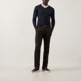Model wearing John Smedley Blenheim Extra Fine Knit Sweater in Hepburn smoke, V-neck, styled with dark trousers and navy trainers