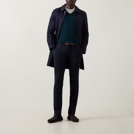 Model wearing John Smedley Blenheim Extra Fine Knit Sweater in Richardson green, styled with navy coat, matching trousers, and dark loafers.