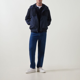 Model wearing Calvin Klein Jeans Mixed Media Logo Windbreaker in Dark Sapphire with blue jeans and white trainers