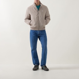 Model wearing Calvin Klein Jeans Harrington Logo Weatherproof Jacket in Vintage Khaki with blue jeans and grey trainers.