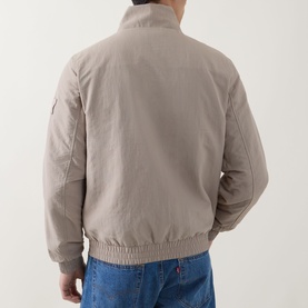 Model wearing Calvin Klein Jeans Harrington Logo Weatherproof Jacket in Vintage Khaki, back view, styled with blue jeans